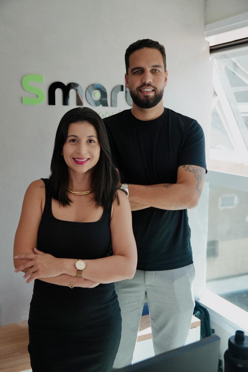Equipe da SmartConsórcios no escritório, diante do letreiro da marca